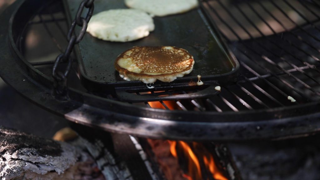 Pancakes cooking over a campfire griddle | camping meals for kids