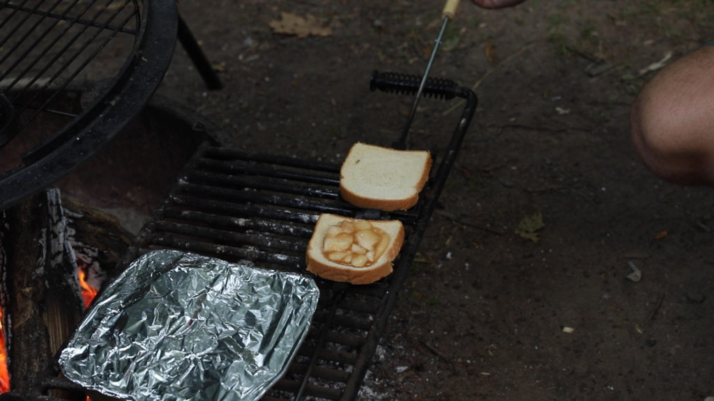 An apple filled camp pie being cooked over a fire while camping
