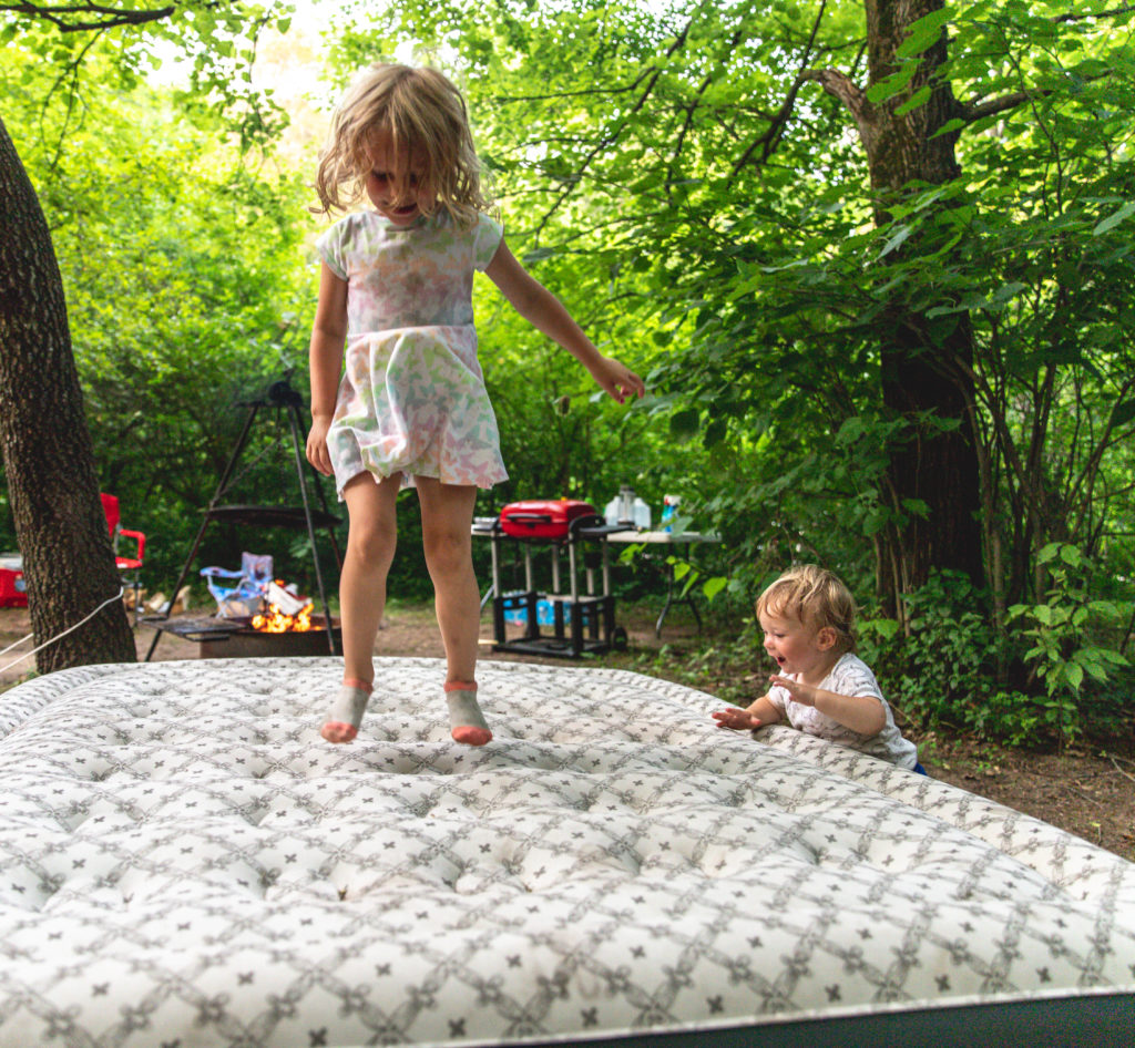 A one year old and four year old playing outside during a family tent camping trip